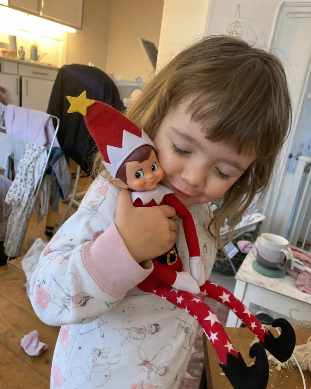 A small girl in pyjamas hugging Pip against her cheek with her eyes closed