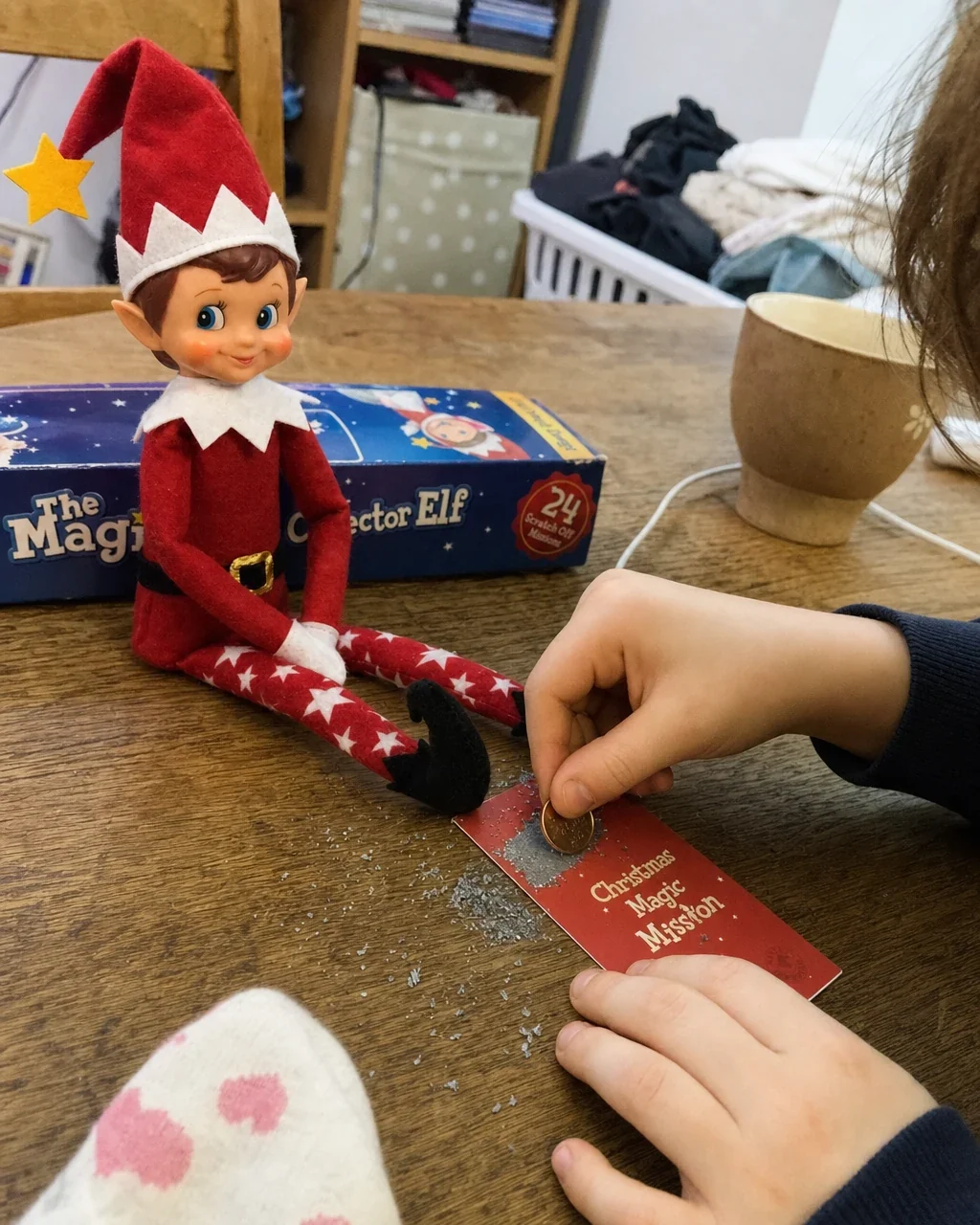 A child scratching the silver panel of a mission card with a coin, shavings on the table