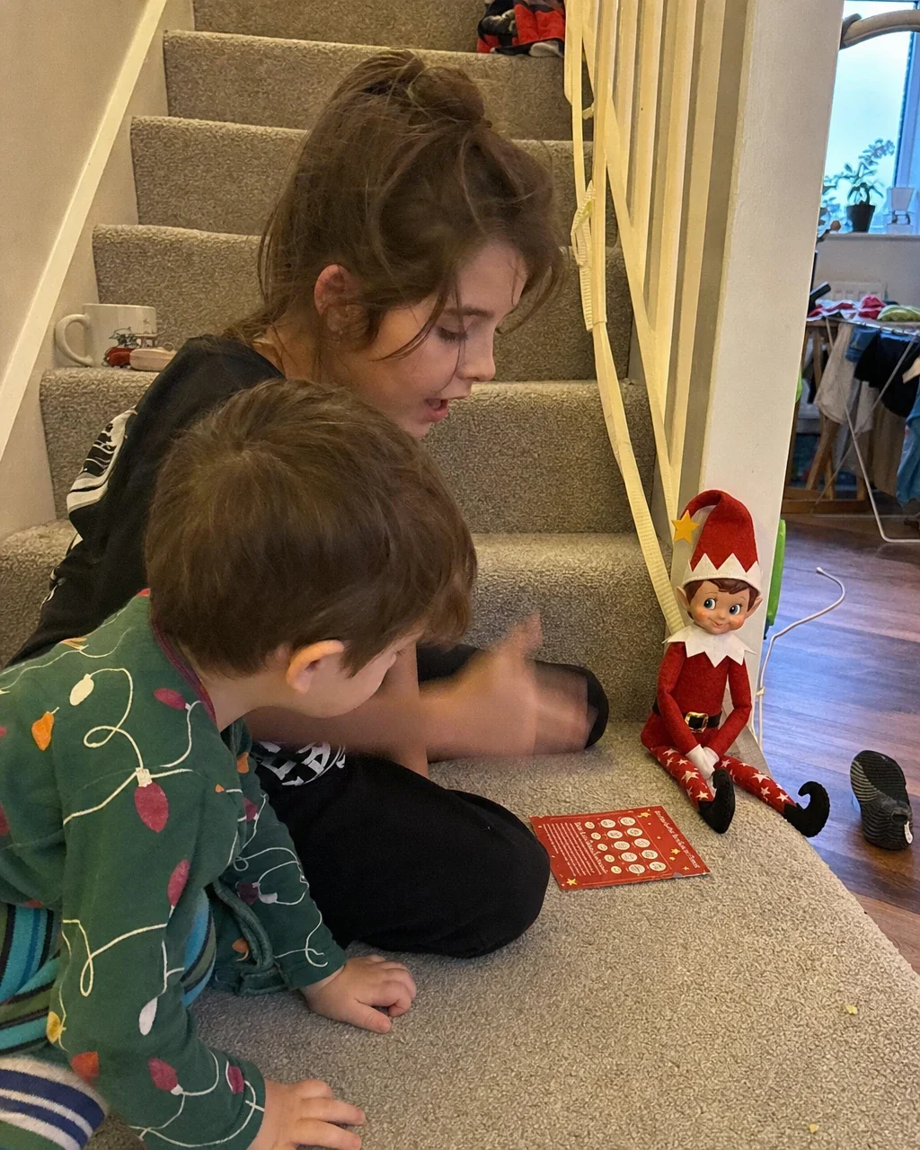 An older sister and her little brother crouched together on the stairs over a mission card
