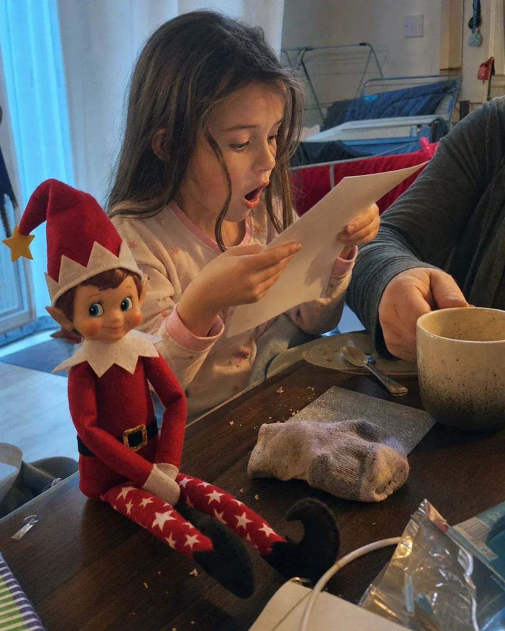 A girl gasping as she reads the letter from Santa at the breakfast table